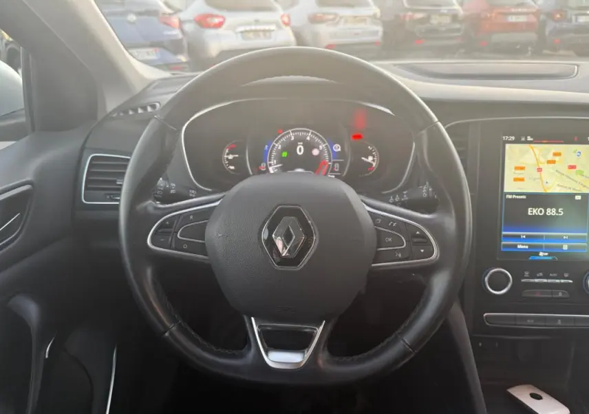 Vue centrée sur le volant cuir de la Renault Mégane IV gris clair, avec tableau de bord numérique et écran tactile visible.
