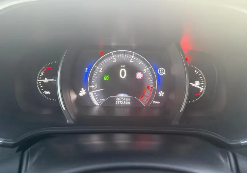 Tableau de bord numérique de Renault Mégane IV gris clair, affichant compteur et jauges avec éclairage bleu et rouge.