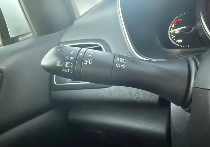 Gros plan sur la commande des phares et clignotants à gauche du volant dans l'habitacle noir d'une Renault Mégane IV gris clair.