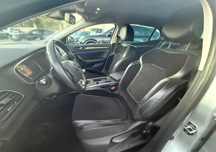 Intérieur de la Renault Mégane IV gris clair, vue côté conducteur montrant sièges sport en cuir et volant cuir.