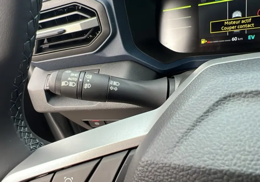 Détail du commodo d’éclairage à gauche du volant cuir dans le tableau de bord du Dacia Duster noir nacré 2026.