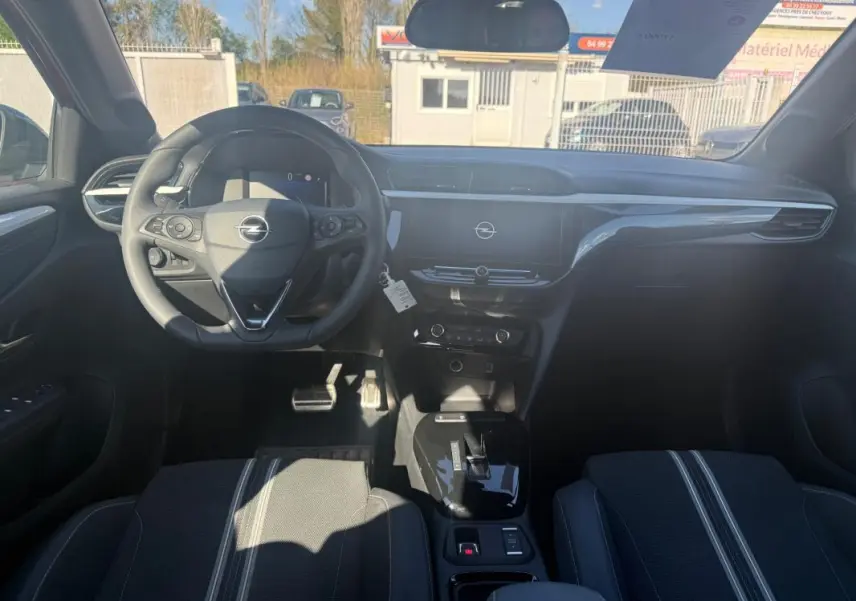 Vue intérieure avant de l’Opel Corsa 2025, tableau de bord noir avec écran central et volant multifonction.