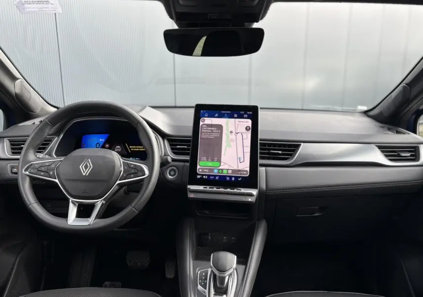 Vue frontale de l'intérieur du Renault Symbioz 2025, tableau de bord noir avec écran tactile vertical et volant multifonction.