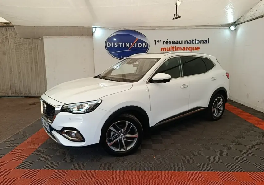 Vue 3/4 avant droit d’un SUV MG EHS blanc, avec jantes alliage et calandre chromée dans un showroom.