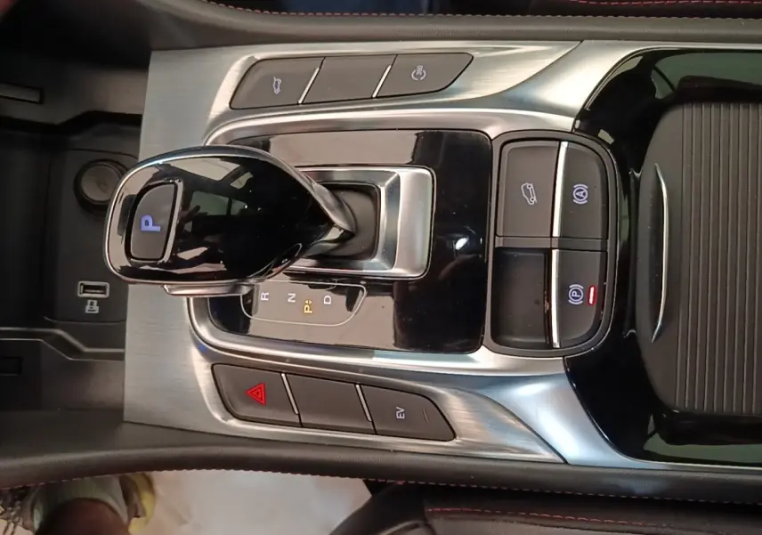 Gros plan sur la console centrale du MG Motor EHS blanc, avec levier de vitesse automatique et boutons de contrôle lumineux.
