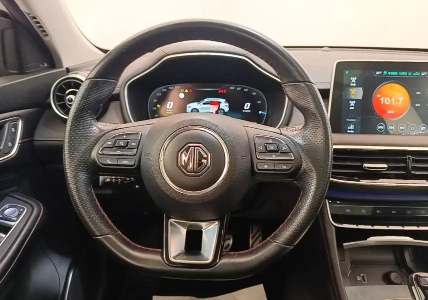 Vue intérieure centrée sur le volant cuir noir du MG Motor EHS 2023 avec tableau de bord digital et écran tactile couleur.