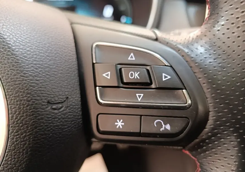 Gros plan sur les commandes multifonctions à droite du volant perforé du MG Motor EHS blanc, version 2023.