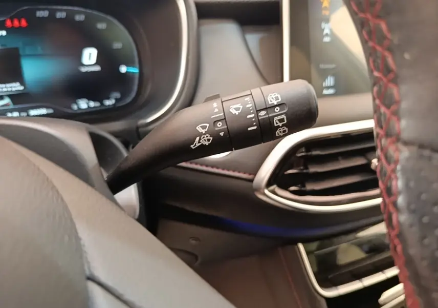 Gros plan sur la commande d’essuie-glace à gauche du volant dans l’habitacle noir du MG Motor EHS blanc 2023.