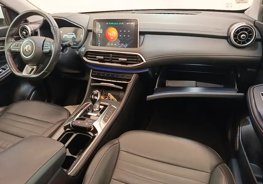Vue intérieure avant du MG Motor EHS 2023, tableau de bord noir avec écran tactile central et volant multifonctions cuir.