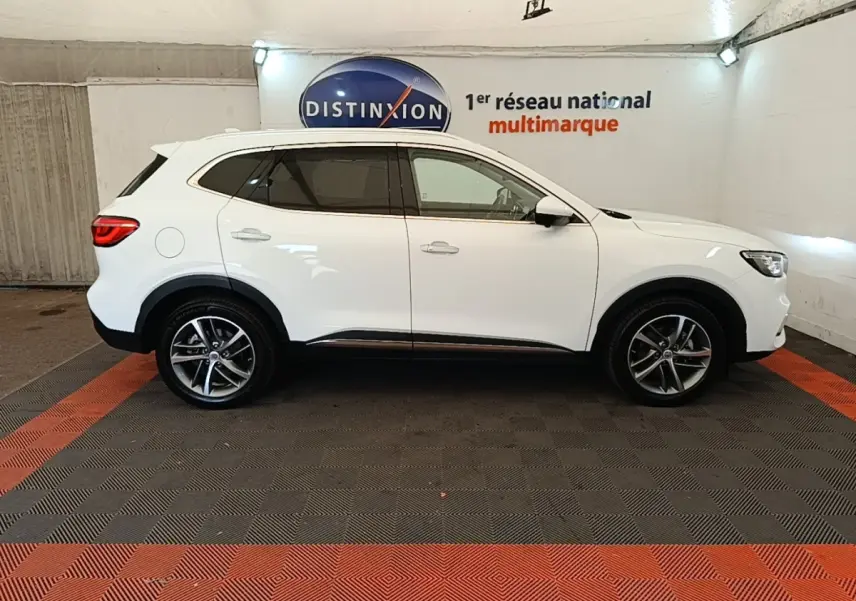 Vue de profil côté droit du SUV blanc MG Motor EHS 2023 dans un showroom avec jantes alliage et vitres teintées.