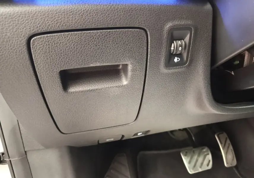 Vue intérieure côté conducteur du MG Motor EHS 2023, montrant le tableau de bord inférieur noir avec commande de réglage des phares.