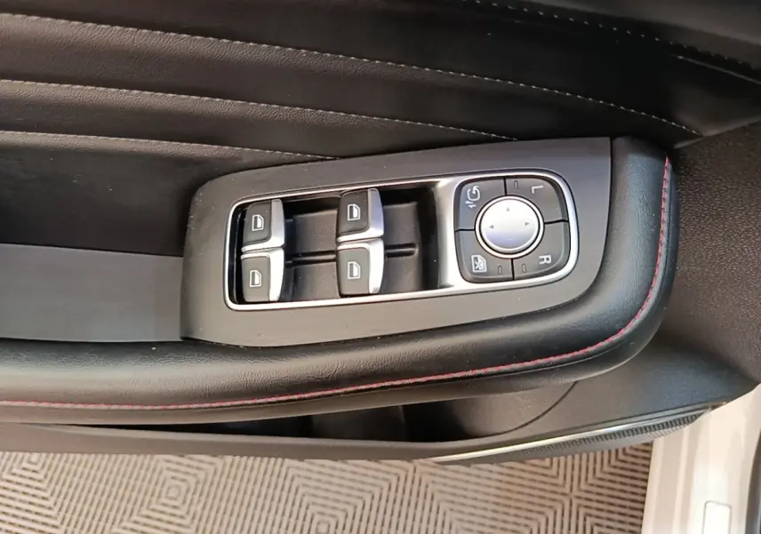 Gros plan sur les commandes des vitres et rétroviseurs côté conducteur du MG Motor EHS blanc 2023.