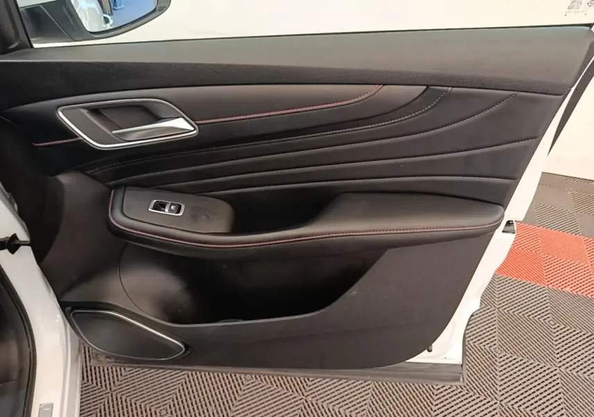 Porte intérieure côté gauche de MG Motor EHS blanc, avec garniture noire et surpiqûres rouges visibles.