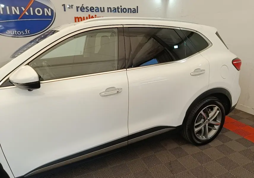 Vue latérale droite du MG Motor EHS blanc 2023, soulignant ses jantes alliage et ses vitres teintées.