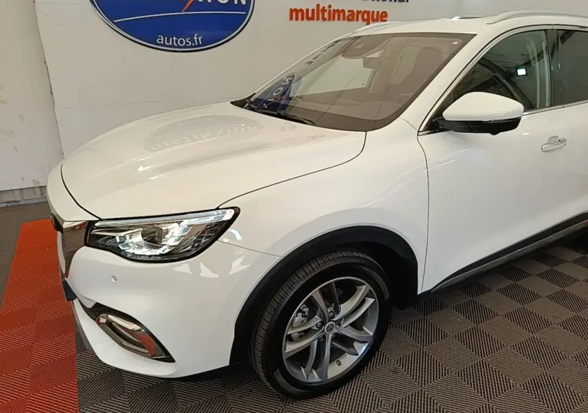 Vue 3/4 avant droit du MG MOTOR EHS blanc, mettant en valeur ses phares LED et jantes alliage modernes.