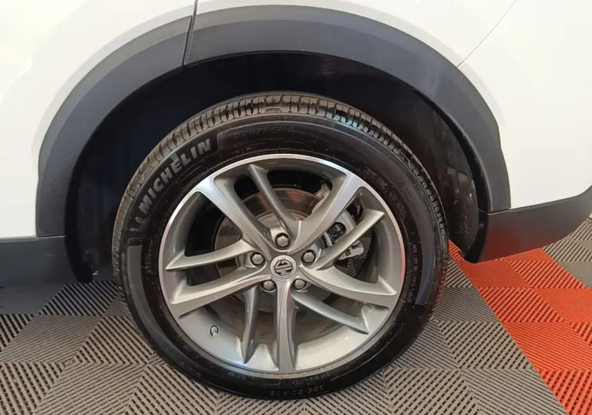 Gros plan sur la roue avant droite d’un MG MOTOR EHS blanc, avec jante alliage et pneu Michelin visible.