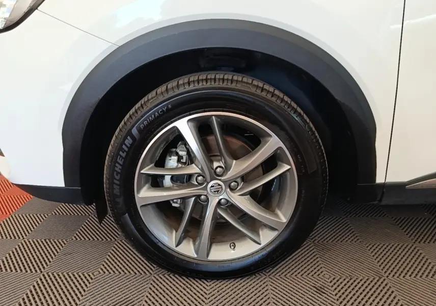 Gros plan sur la roue avant gauche en alliage gris d’un MG Motor EHS blanc avec passage de roue noir.