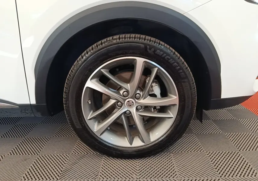 Gros plan sur la roue avant droite d’un MG Motor EHS blanc, jante alliage argentée à 5 doubles branches.