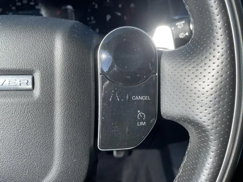 Gros plan sur les commandes de régulateur de vitesse à droite du volant en cuir perforé du Range Rover Velar gris métal 2020.