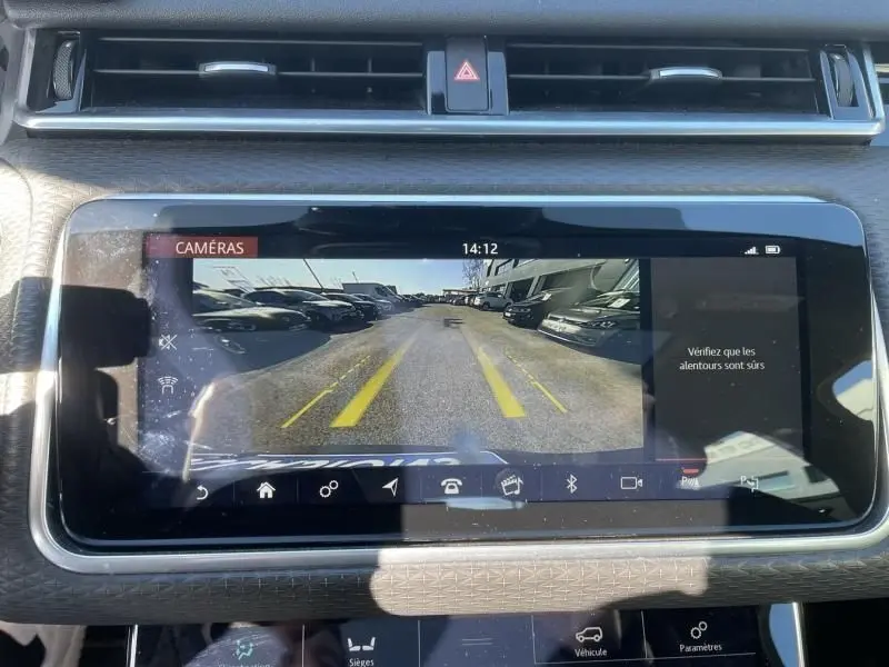Écran central du Range Rover Velar 2020 montrant la caméra de recul avec lignes de guidage jaunes sur parking extérieur.