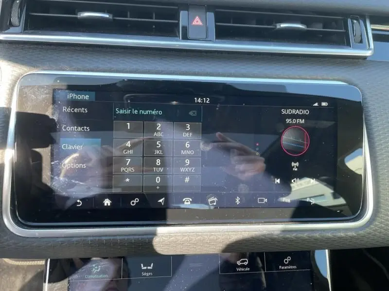 Écran tactile central du Range Rover Velar gris métal 2020, affichant le menu téléphone et radio FM.