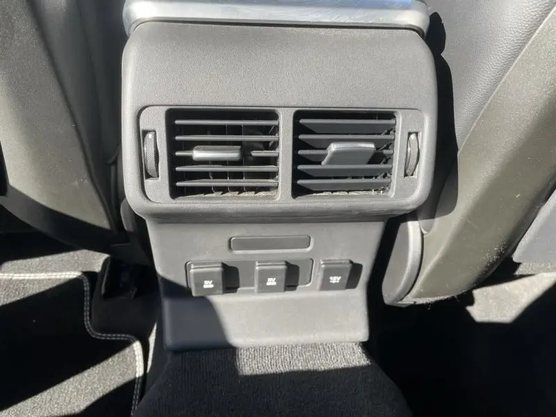 Détail des aérateurs et prises 12V à l'arrière en plastique noir dans un Range Rover Velar gris métal 2020.