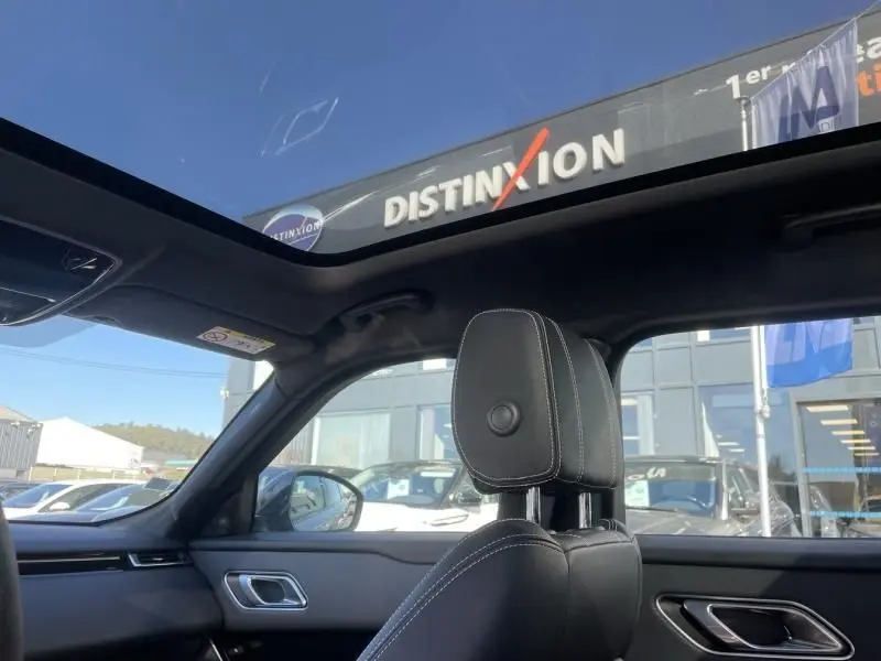 Intérieur du Range Rover Velar gris métal 2020, vue côté conducteur avec toit panoramique et sellerie noire.
