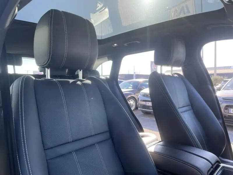 Gros plan sur les sièges avant en cuir noir avec surpiqûres blanches du Range Rover Velar gris métal 2020, vue intérieure.