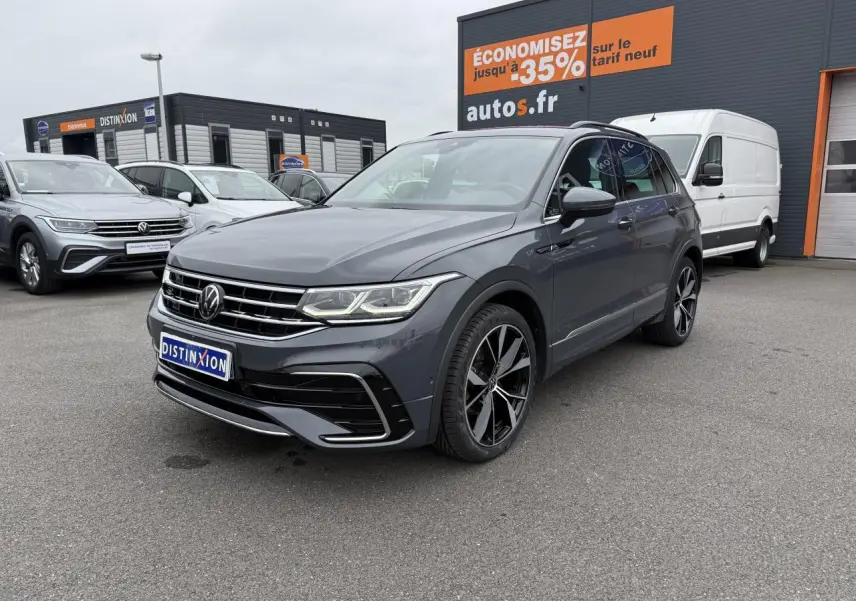 Volkswagen Tiguan gris dauphin en 3/4 avant droit avec jantes alliage noires et calandre chromée visible.