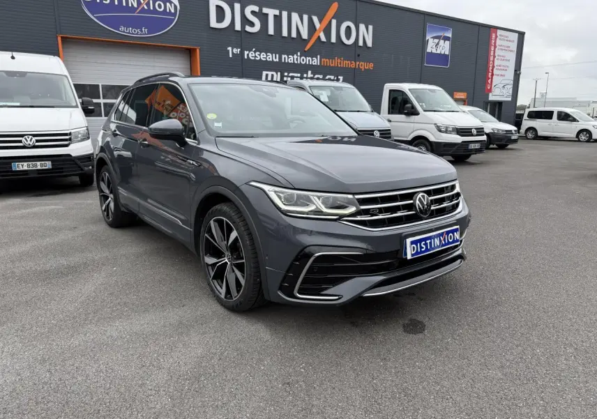 Volkswagen Tiguan 2.0 TDI gris dauphin en 3/4 avant avec jantes alliage 20 pouces et calandre R-Line visible.