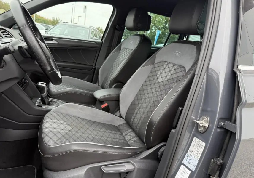 Vue intérieure côté conducteur du Volkswagen Tiguan gris Dauphin 2023, sièges sport en tissu et microfleece avec logo R brodé.