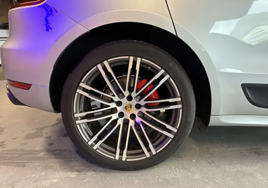 Gros plan sur la roue arrière droite argentée d'un Porsche Macan 3.0 360 GTS avec étrier de frein rouge visible.