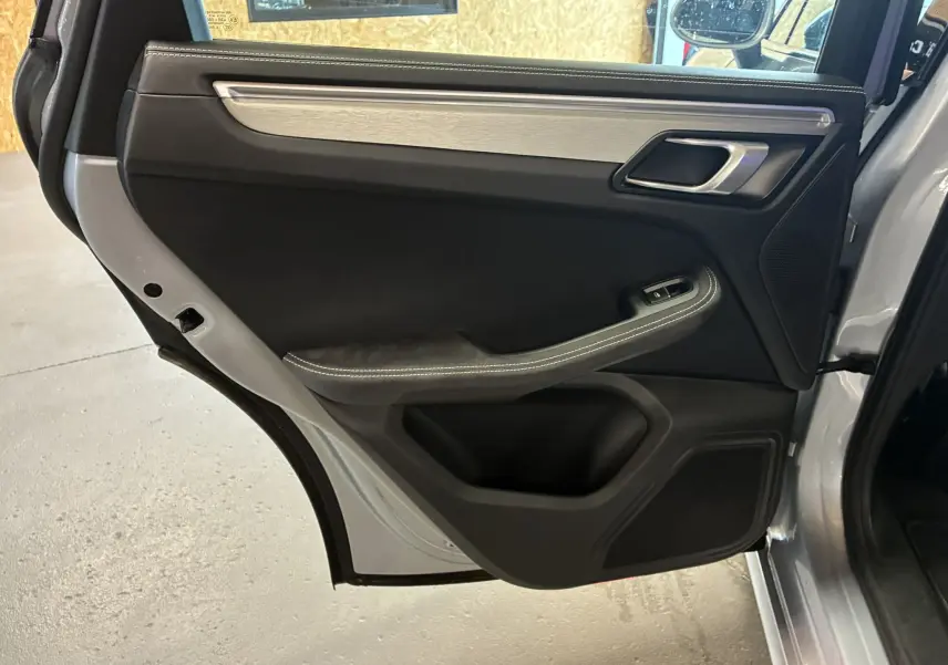 Vue intérieure de la porte arrière gauche grise du Porsche Macan 3.0 360 GTS avec garniture noire et insert aluminium brossé.