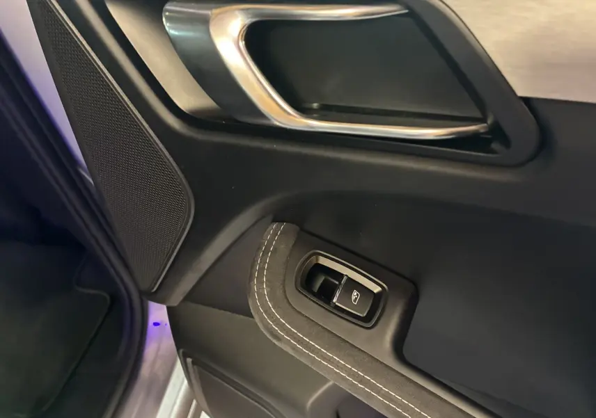 Détail de la poignée intérieure et commande de lève-vitre côté gauche d'une Porsche Macan GTS 2017 avec finition cuir noir et surpiqûres blanches.