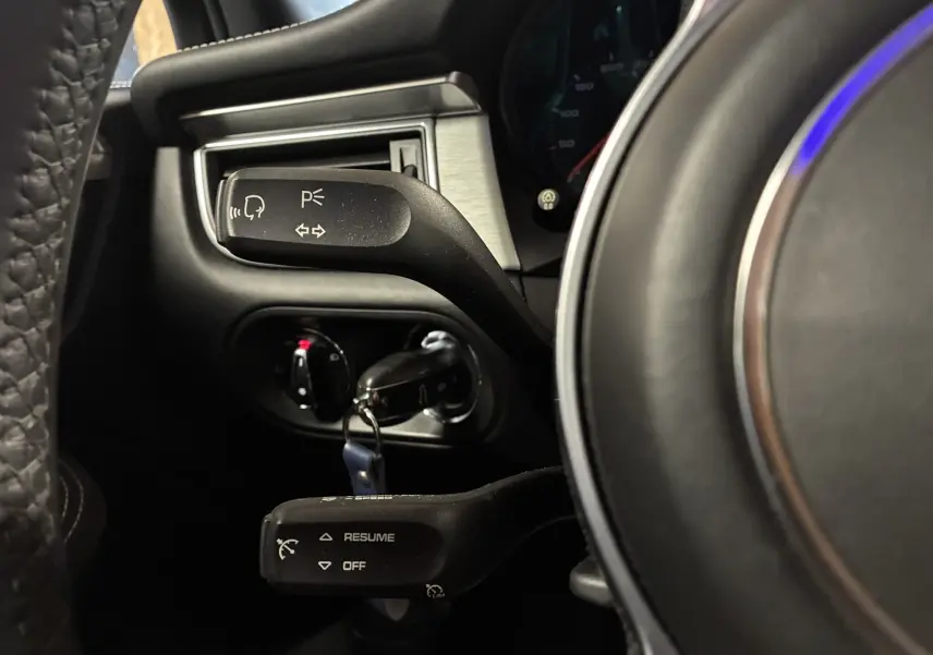 Gros plan sur les commandes au volant noir du Porsche Macan GTS 2017, montrant les leviers de clignotants et régulateur de vitesse.