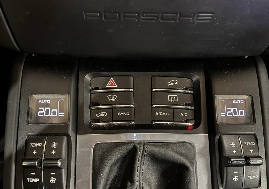 Console centrale noire du Porsche Macan GTS 2017 avec commandes climatisation affichant 20°C et logo Porsche en haut.