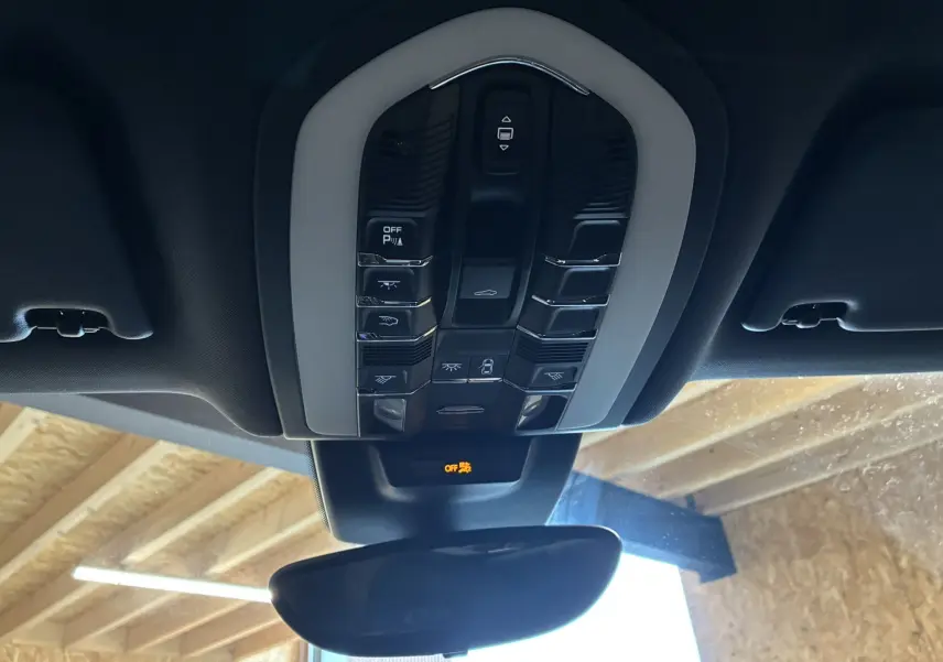 Vue en contre-plongée du panneau de commandes de toit intérieur noir et gris du Porsche Macan GTS 2017 avec rétroviseur central.