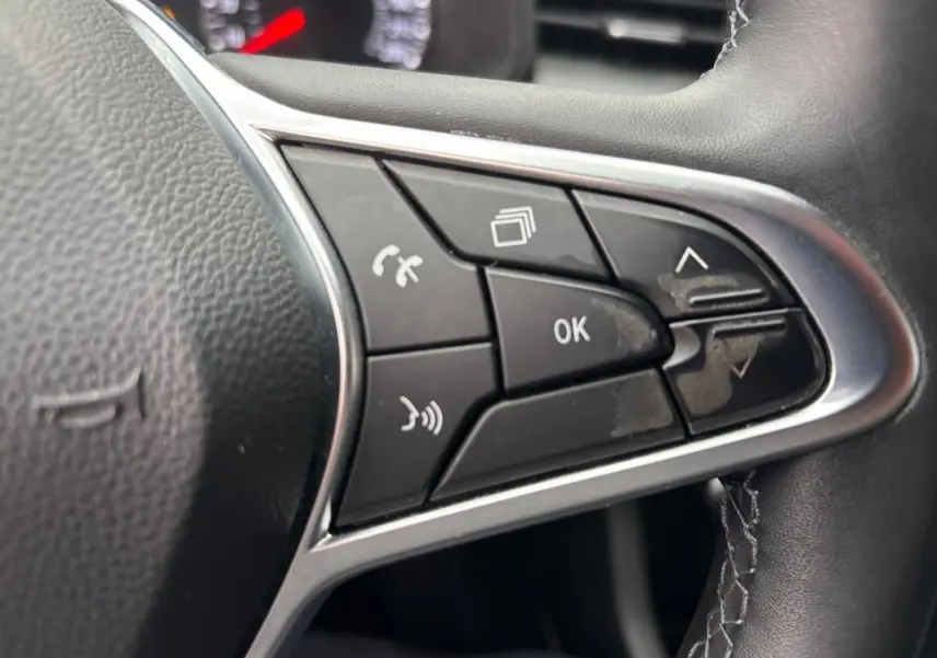 Gros plan sur les commandes multifonctions noires du volant de la Renault Clio gris foncé, version V TCe 90 Equilibre 2022.