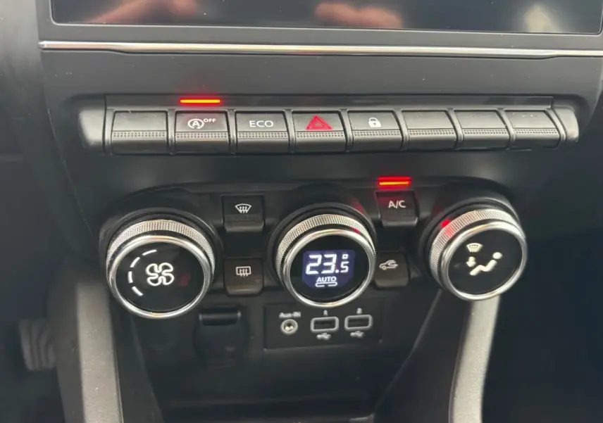 Gros plan sur la console centrale de la Renault Clio V TCe 90, avec commandes de climatisation et boutons fonctionnels.