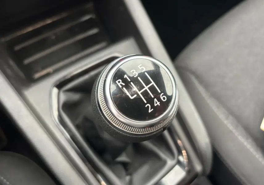 Gros plan sur le levier de vitesses manuel noir de la Renault Clio gris foncé, avec marquage des six rapports et marche arrière.