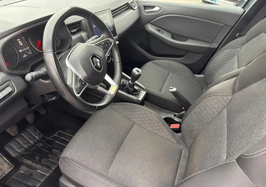 Intérieur de Renault Clio V TCe 90 Equilibre 2022, vue côté conducteur montrant volant, sièges gris foncé et levier de vitesse manuel.