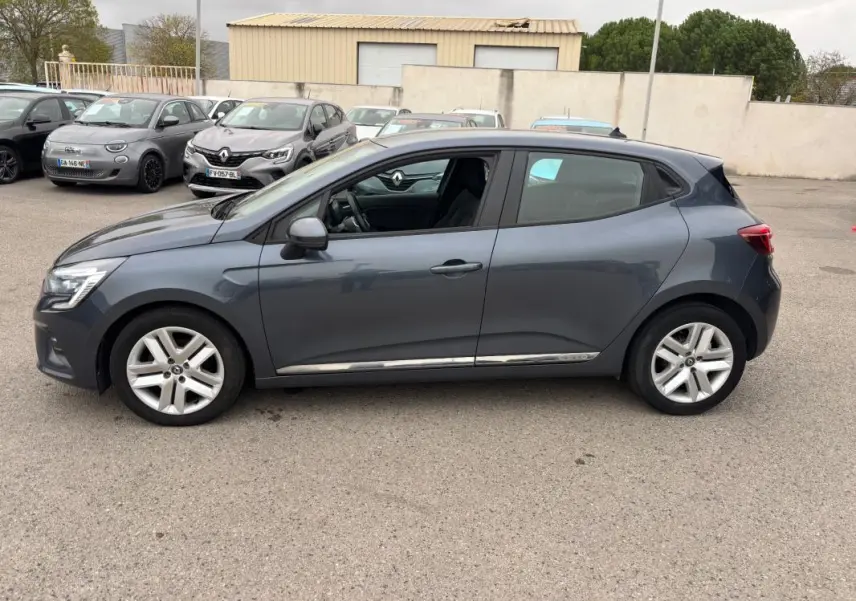 Profil côté gauche d'une Renault Clio gris foncé 2022, finition V TCe 90 Equilibre, sur parking extérieur.