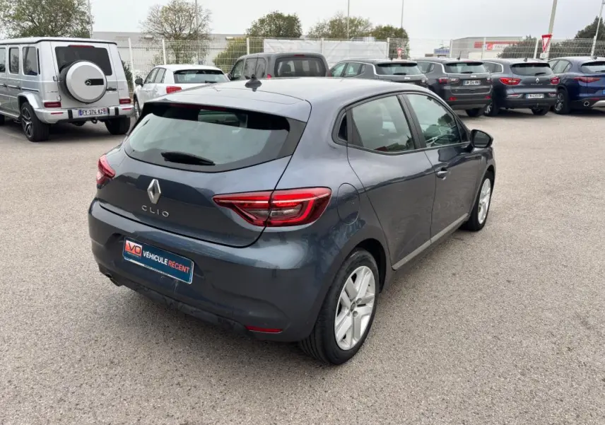 Vue 3/4 arrière droite d'une Renault Clio gris foncé 2022, avec feux arrière allumés sur parking extérieur.