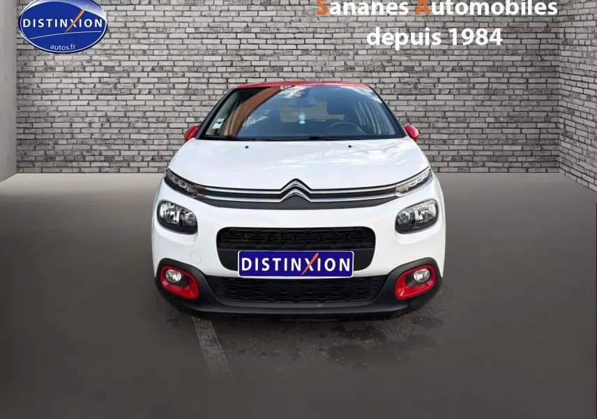 Vue avant d'une Citroën C3 blanche avec toit et rétroviseurs rouges, détails rouges sur le pare-chocs.