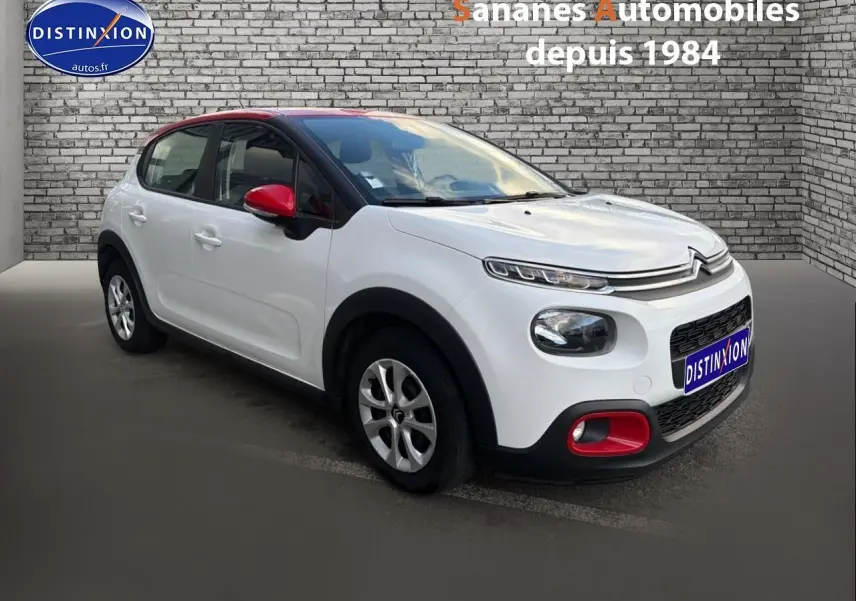Citroën C3 blanche vue 3/4 avant droit avec toit noir et coques de rétroviseurs rouges.