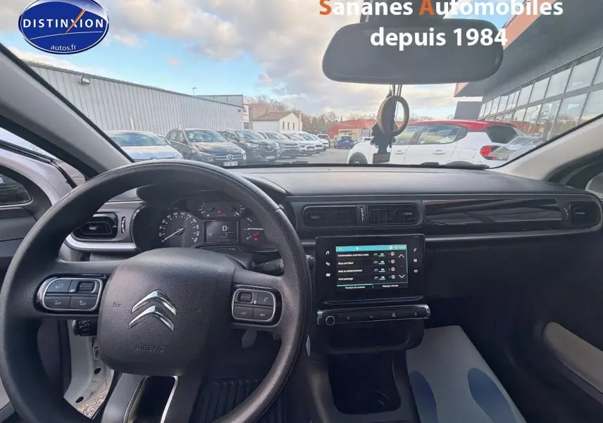 Vue intérieure avant du tableau de bord de la Citroën C3 blanche, avec volant et écran tactile central allumé.