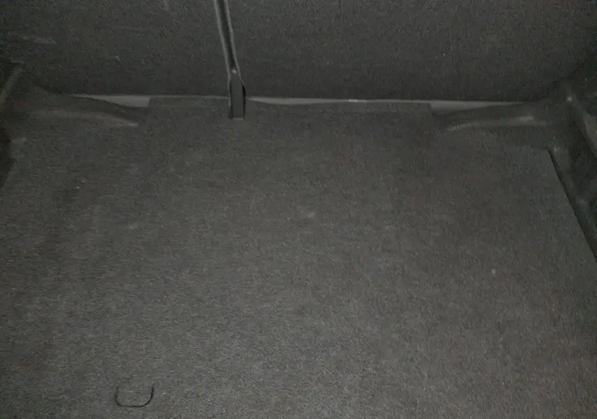 Coffre vide de l'Audi A1 Sportback noir, vue intérieure montrant le revêtement de sol en tissu gris foncé.