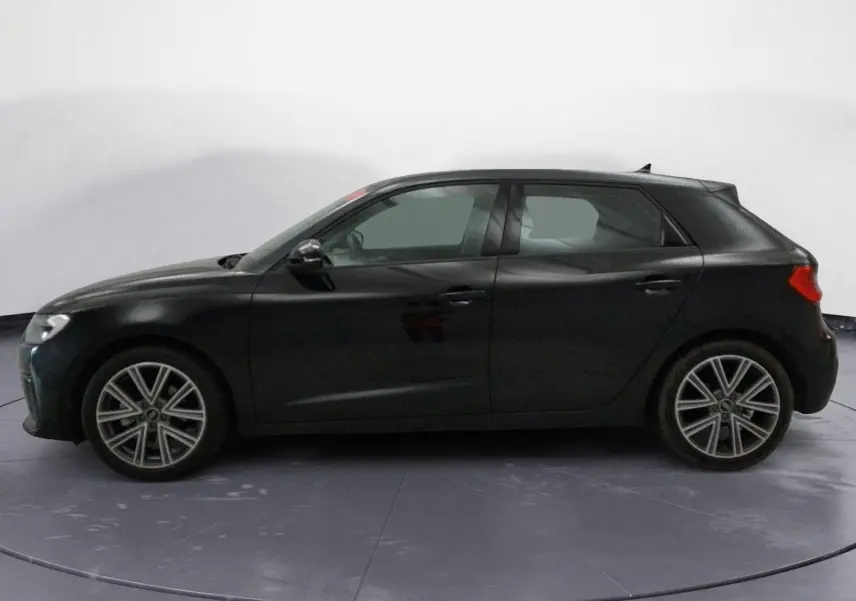 Profil gauche d'une Audi A1 Sportback noire 2023 avec jantes alliage et lignes épurées, en intérieur neutre.