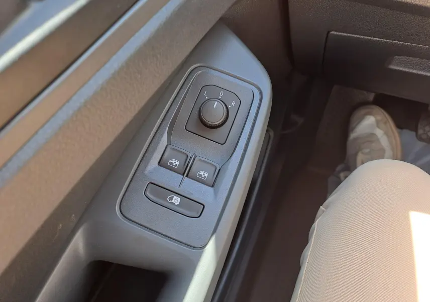 Gros plan sur les commandes des rétroviseurs et vitres côté conducteur du Volkswagen Caddy Cargo Maxi blanc 2026.