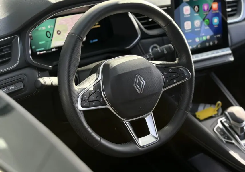 Vue rapprochée du volant noir en cuir du Renault SYMBIOZ 2025 avec tableau de bord numérique et écran tactile central.
